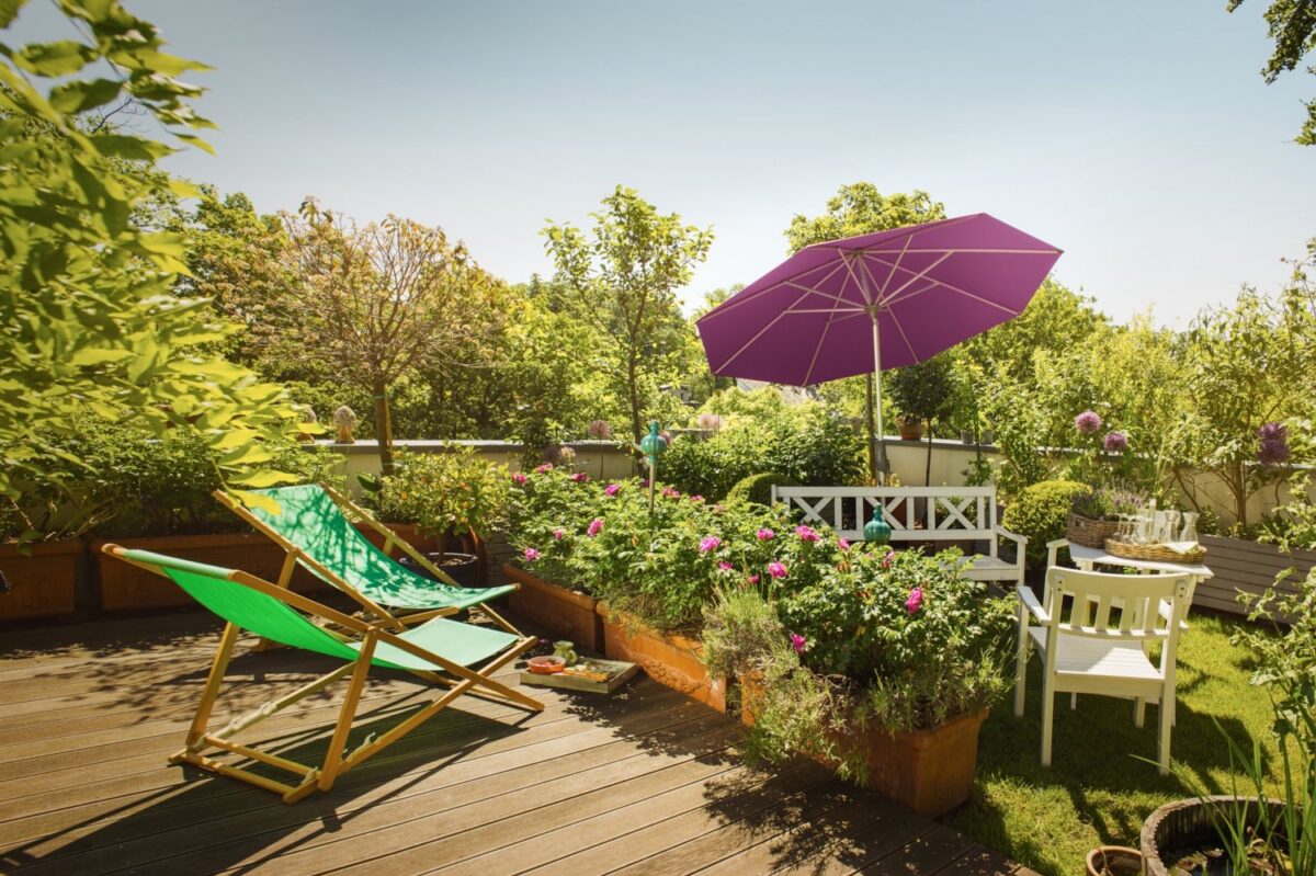 Sonnenschirm neben Gartenbank und Gartenstuhl