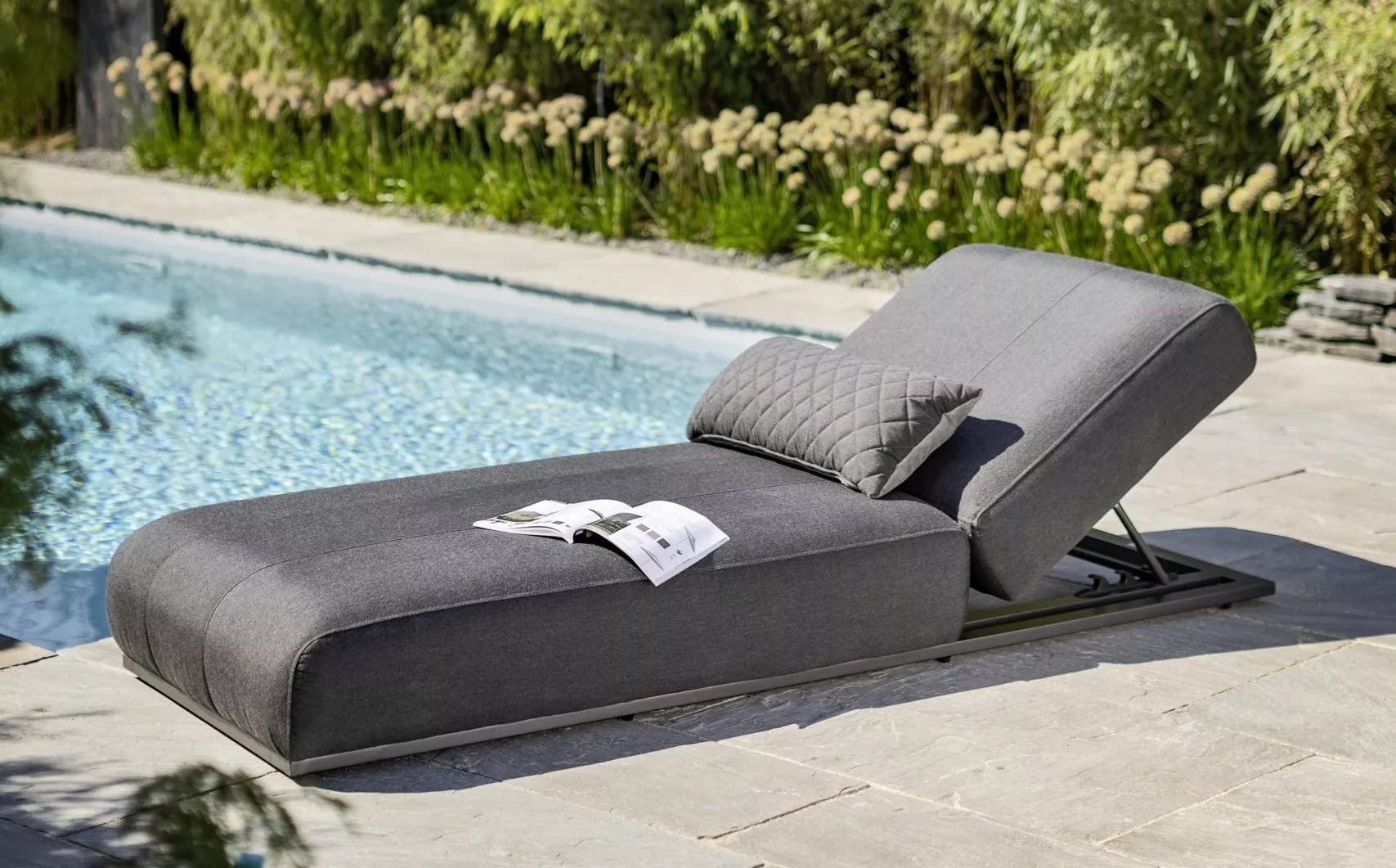 Die Kettler Sonnenliege "Ego" mit komfortablem Polster aus Sunbrella® Sooty vor einem Pool