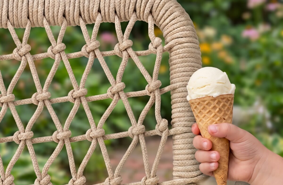 Eine Kinderhand mit Eis dicht an einem Rope-Gartenstuhl